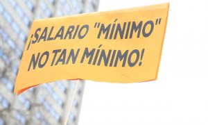 Una mujer, que no aparece en la imagen, sostiene una pancarta donde se puede leer “¡Salario mínimo, no tan mínimo!” como signo de protesta en la concentración convocada frente al Ministerio de Asuntos Económicos, en Madrid. E.P.