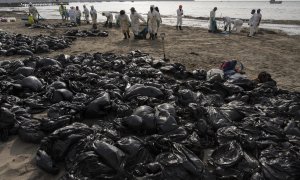 Equipos de limpieza trabajan para retirar petróleo de una playa anexa al balneario de verano de Ancón, en el norte de Lima, el 20 de enero de 2022.