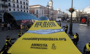 Amnistía Internacional despliega una lona en la Puerta del Sol