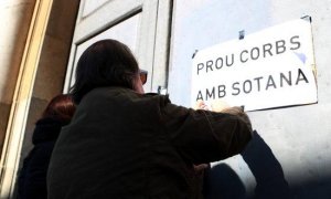 Un home enganxant cartells en la protesta per denunciar els abusos sexuals a menors d'eclesiàstics.