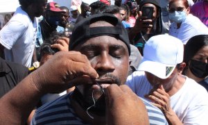 Migrantes se cosen hoy la boca mientras participan en una manifestación en la ciudad de Tapachula, estado de Chiapas (México).