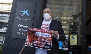 Carlos San Juan, el hombre de 78 años que ha recogido más de 600.000 apoyos con su campaña 'Soy Mayor, No Idiota', posa delante de una sucursal bancaria con un cartel que simula la entrega de sus firmas a los bancos, tras registrarlas en el Ministerio de