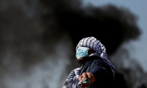 18/02/2022 Un manifestante con el rostro cubierto mira durante una protesta contra los asentamientos judíos en la aldea de Beta, cerca de Naplusa, en la Cisjordania ocupada por Israel