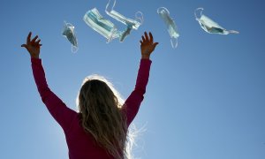 23/2/22-Una mujer tira mascarillas al aire, a 8 de febrero de 2022, en Madrid (España).