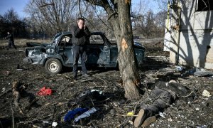 Un hombre reacciona al teléfono mientras está de pie junto a un cuerpo tendido en el suelo después de los bombardeos en la ciudad de Chuguiv, en el este de Ucrania, el 24 de febrero de 2022.