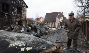 Un anciano camina entre los restos de un avión no identificado que se estrelló contra una casa en una zona residencial de Kiev, después de que Rusia lanzara una operación militar masiva contra Ucrania, este viernes 25 de febrero.