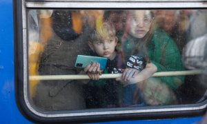 Una mujer y su hijo miran desde un tren de evacuación de Kiev a hacia la ciudad de Lviv (Leópolis) en la estación central de trenes de Kiev, en el segundo día la invasión rusa.