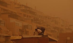 Unas personas trabajan en Aguadulce, Roquetas de Mar (Almería), que ha amanecido este martes bajo los efectos de una intensa calima.