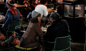 Dos personas en una terraza en la Plaza de Santa Ana para celebrar la llegada de la Nochebuena, a 24 de diciembre de 2021, en Madrid (España). A pesar de las nuevas restricciones, como el uso de la mascarilla en exteriores, que entra en vigor hoy, varias