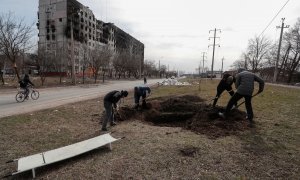 Un grupo de personas cava una tumba en una calle de la ciudad sitiada de Mariupol, Ucrania, 20 de marzo de 2022.