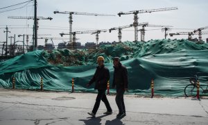 Dos trabajadores migrantes caminan cerca de una obra en Pekín. EFE/EPA/WU HONG