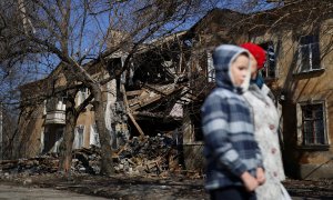 24/03/2022 Natalia y su hijo Micha, de 9 años, caminan frente a un edificio bombardeado en su barrio en Mykolaiv, Ucrania, este 24 de marzo
