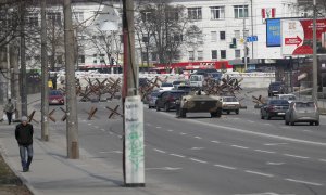 24/03/2022-Los coches transitan en una calle junto a vehículos blindados del ejército cerca de barricadas en las afueras de Kiev, Ucrania, este 24 de marzo