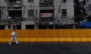 28/03/2022-Un hombre con equipo de protección camina frente al recinto en cuarentena, en Shanghai, China, el 28 de marzo de 2022
