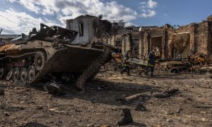 Rescatistas ucranianos pasan junto a un tanque ruso destruido junto a una estación de tren en la ciudad recuperada por el ejército ucraniano de Trostyanets este 30 de marzo de 2022.