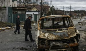 La gente camina por una calle con varios cadáveres en el suelo en Bucha, al noroeste de Kiev, mientras Ucrania dice que las fuerzas rusas están haciendo una "retirada rápida" de las áreas del norte alrededor de Kiev y la ciudad de Chernigiv, el 2 de abril