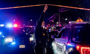 Un oficial del Departamento del Sheriff del condado de Sacramento sostiene una cinta policial para permitir que un vehículo ingrese a la escena del crimen afuera de una iglesia donde un hombre mató a tiros a cuatro personas, incluidos tres de sus hijos, a