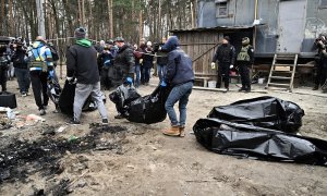 Los trabajadores de la ciudad llevan bolsas para cadáveres con seis cuerpos parcialmente quemados encontrados en la ciudad de Bucha el 5 de abril de 2022, ya que las autoridades ucranianas dicen que se han recuperado más de 400 cuerpos civiles de la regió