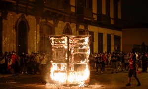 06/04/2022 - Manifestantes observan cómo arde la estructura de un vendedor ambulante durante una protesta contra el presidente de Perú, Pedro Castillo, después de que éste decretara el toque de queda que fue levantado tras el desafío generalizado en las c
