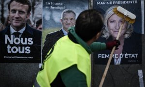 Un empleado de una empresa de exhibición coloca carteles de la campaña oficial de los candidatos presidenciales (desde la izquierda) ¡El presidente francés del partido centrista Emmanuel Macron La Republique en Marche (LREM), el agrarista francés Resiston