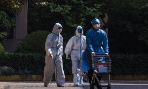 (12/02/2022) Trabajadores comunitarios caminan por una zona residencial con el traje de protección.