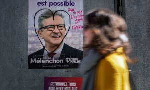 Una mujer camina en París el 9 de abril de 2022 frente a un cartel de campaña de La Francia Insumisa (LFI), partido liderado por Jean-Luc Mélenchon.