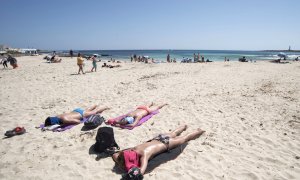 16/04/2022 Varias personas disfrutan de una jornada soleada en la playa de Punta Prima, Menorca, este Sábado Santo