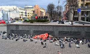 Un vagabundo duerme mientras las palomas se calientan junto a las rejillas de ventilación de un centro comercial subterráneo, centro de Kiev, a 9 de marzo de 2021.