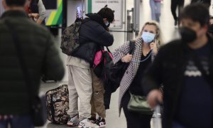 Dos personas, con maletas, se abrazan junto al control de equipajes, en el día en que arranca la operación salida de Semana Santa 2022, en la estación Madrid - Puerta de Atocha