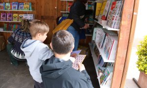 Un nen i el seu pare miren llibres en un estand.