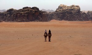 En el desierto de Wadi Rum, en Jordania, un beduino acompaña a un turista en camello.
