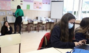 Una alumna, con mascarilla quirúrgica, trabaja con un ordenador portátil.