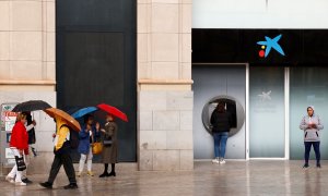 Una mujer utiliza el cajero automático de una oficina de CaixaBank en el centro de Málaga. REUTERS/Jon Nazca