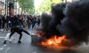 Los manifestantes se reúnen alrededor de un objeto en llamas en la carretera al margen de la manifestación anual del Primero de Mayo (Día del Trabajo), que marca el Día Internacional de los Trabajadores, en París el 1 de mayo de 2022.