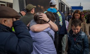 Refugiados ucranianos se abrazan este martes 3 de mayo de 2022 tras llegar al estacionamiento de un centro comercial en Zaporiyia (Ucrania).