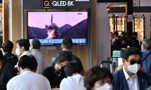 La gente mira una pantalla de televisión que muestra una transmisión de noticias con imágenes de archivo de una prueba de misiles de Corea del Norte, en una estación de tren en Seúl el 7 de mayo de 2022, después de que Corea del Norte disparara un misil b