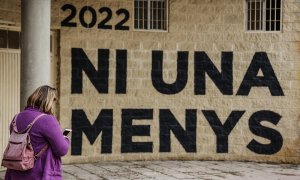Una mujer pasa por delante de una pared donde se puede leer "Ni una menos" en un acto en memoria de las víctimas de violencia de género y sus hijas e hijos, en el antiguo cauce del Turia, a 8 de marzo de 2022, en Valencia, Comunidad Valenciana