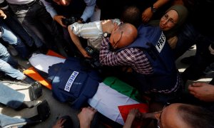 Varios periodistas junto al cuerpo de la reportera de Al Yazira Shireen Abu Akleh, asesinada por disparos del ejército israelí durante una redada, a 11 de mayo de 2022.