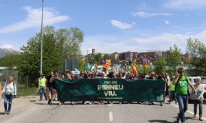 La capçalera de la mobilització en contra dels Jocs d'hivern 2030, convocada per la Plataforma Stop JJOO, sortint de la zona industrial de Puigcerdà i on es veu els edificis de la localitat al fons.