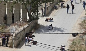 Los palestinos se ponen a cubierto durante los enfrentamientos con las fuerzas de seguridad israelíes en la ciudad cisjordana de Jenin, el 13 de mayo de 2022.