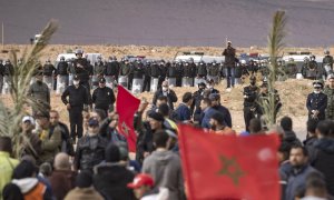Las fuerzas de seguridad marroquíes montan guardia mientras los agricultores marroquíes protestan en la ciudad de Figuig el 18 de marzo de 2021, después de que las autoridades argelinas expulsaran a los cultivadores de dátiles del territorio argelino, una