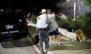 Una mujer que ofrece abrazos y oraciones abraza a un guardabosques de Texas fuera del Centro Cívico Ssgt Willie de Leon, donde los estudiantes habían sido transportados desde la Escuela Primaria Robb después de un tiroteo, en Uvalde, Texas , EE. UU. 24 de