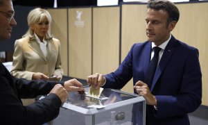 El presidente de Francia, Emmanuel Macron (R), emite su voto seguido por su esposa, la primera dama francesa Brigitte Macron (C), en las elecciones parlamentarias francesas en un colegio electoral en Le Touquet, en el norte de Francia, el 12 de junio de 2