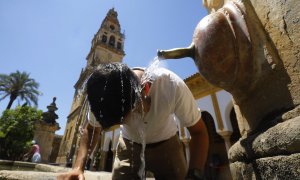 un turista se refresca en una de las fuentes del Patio de los Naranjos de la Mezquita catedral de Córdoba para aliviar las altas temperaturas.