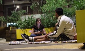 Dues voluntàries d'Arrels conversen amb l'Omar, que dorm al carrer a Barcelona.