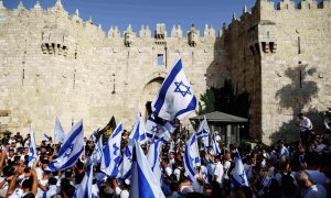 Los israelíes bailan y cantan mientras sostienen banderas nacionales israelíes junto a la puerta de Damasco en la ciudad vieja de Jerusalén.