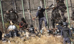 Un agente marroquí golpea desde territorio español con un palo a los migrantes que lograron saltar la valla de Melilla el pasado viernes.