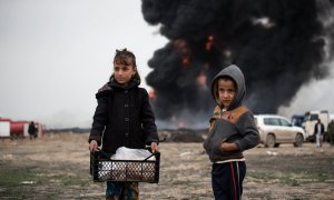 Niños llevan comida a los bomberos mientras intentan extinguir los pozos de petróleo incendiados por los miembros de ISIS mientras se retiraban, en Qayyara, Irak, el miércoles 15 de marzo de 2017.