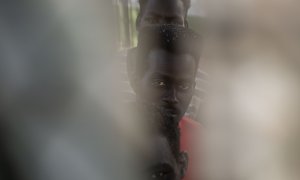 Tres de los migrantes que lograron cruzar a Melilla el pasado viernes, visto por una rendija en el Centro de Estancia Temporal para Migrantes (CETI), donde están en en cuarentena.