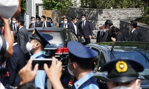 Un coche fúnebre (izquierda) que lleva el cuerpo del asesinado ex primer ministro japonés Shinzo Abe llega a su residencia, mientras su esposa Akie Abe y los miembros principales del gobernante Partido Liberal Democrático (derecha) se inclinan, en Tokio,